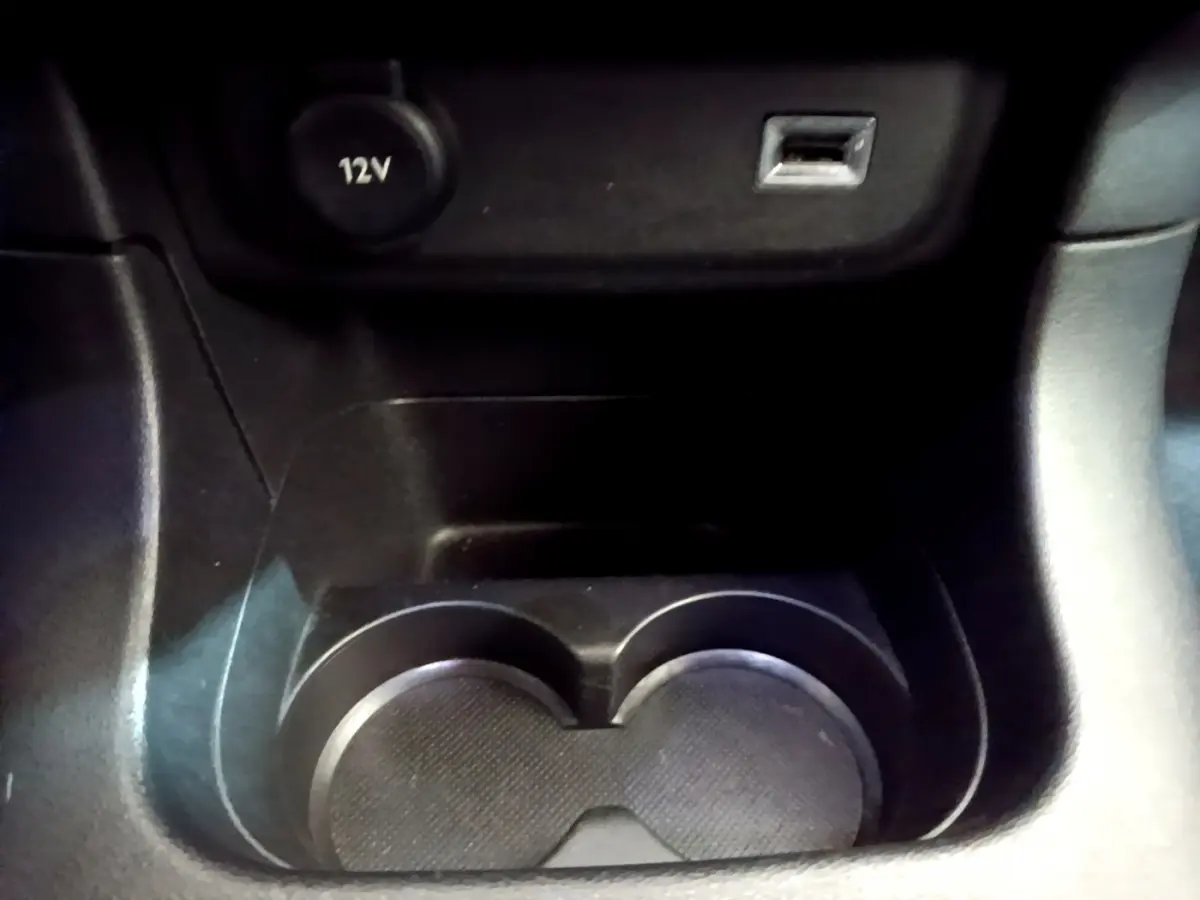 Gros plan sur la console centrale noire de la Citroën C3 2019, montrant porte-gobelets, prise 12V et port USB.