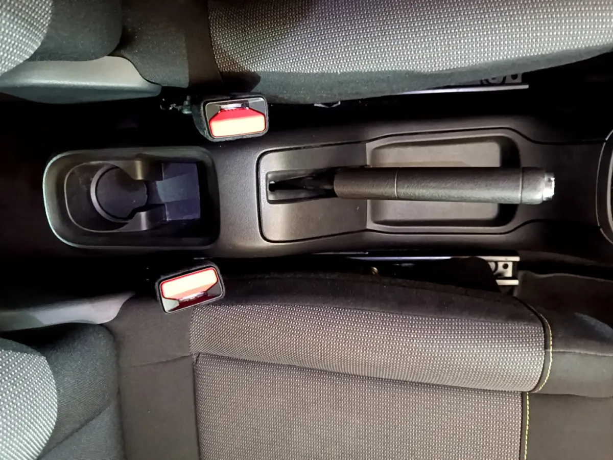 Vue plongeante sur la console centrale noire avec frein à main et ceintures de sécurité rouges d'une Citroën C3 2019.