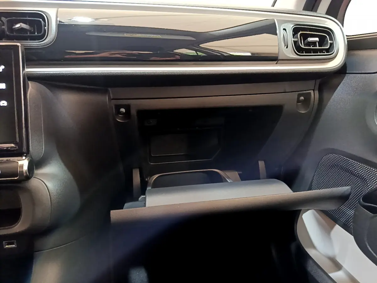 Intérieur de la Citroën C3 blanc, vue du tableau de bord côté passager avec boîte à gants ouverte et aérateurs rectangulaires.