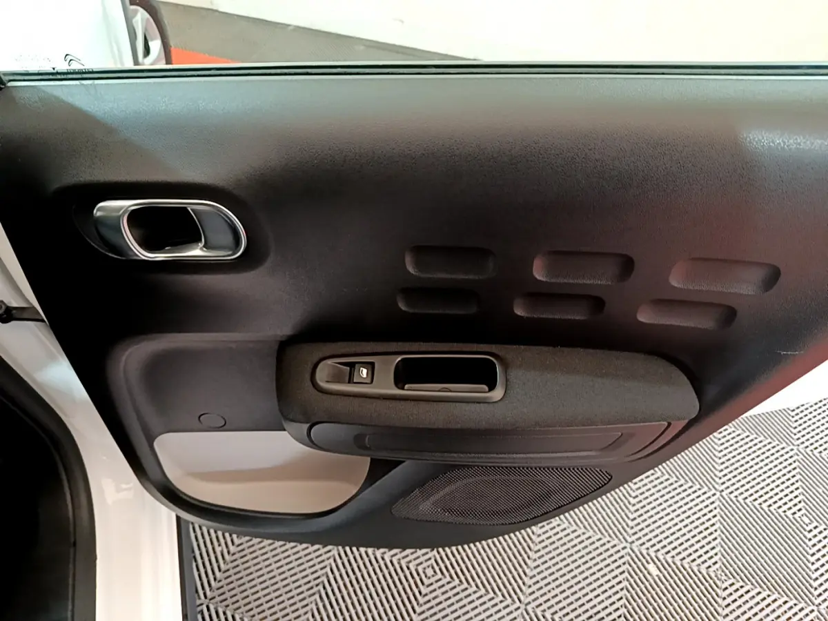 Gros plan sur la porte avant gauche blanche de la Citroën C3 2019 avec poignée et commande de vitre noire.