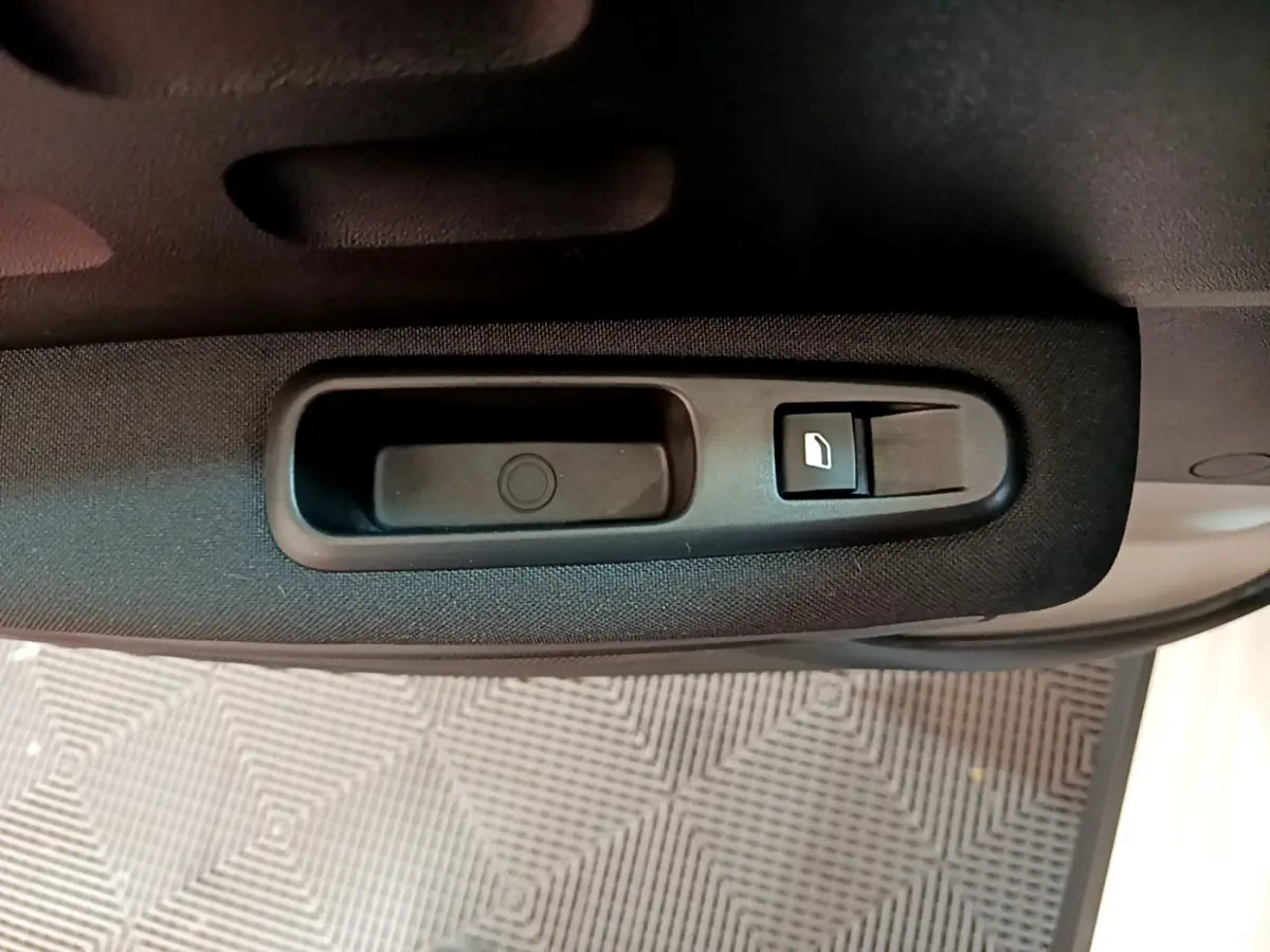 Gros plan sur la commande de lève-vitre côté conducteur de la Citroën C3 blanche, intérieur tissu noir.