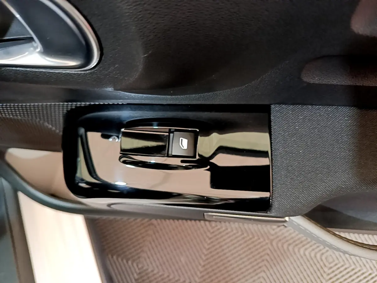 Gros plan sur la commande de lève-vitre noir brillant côté conducteur dans l'habitacle d'une Citroën C3 blanche 2019.