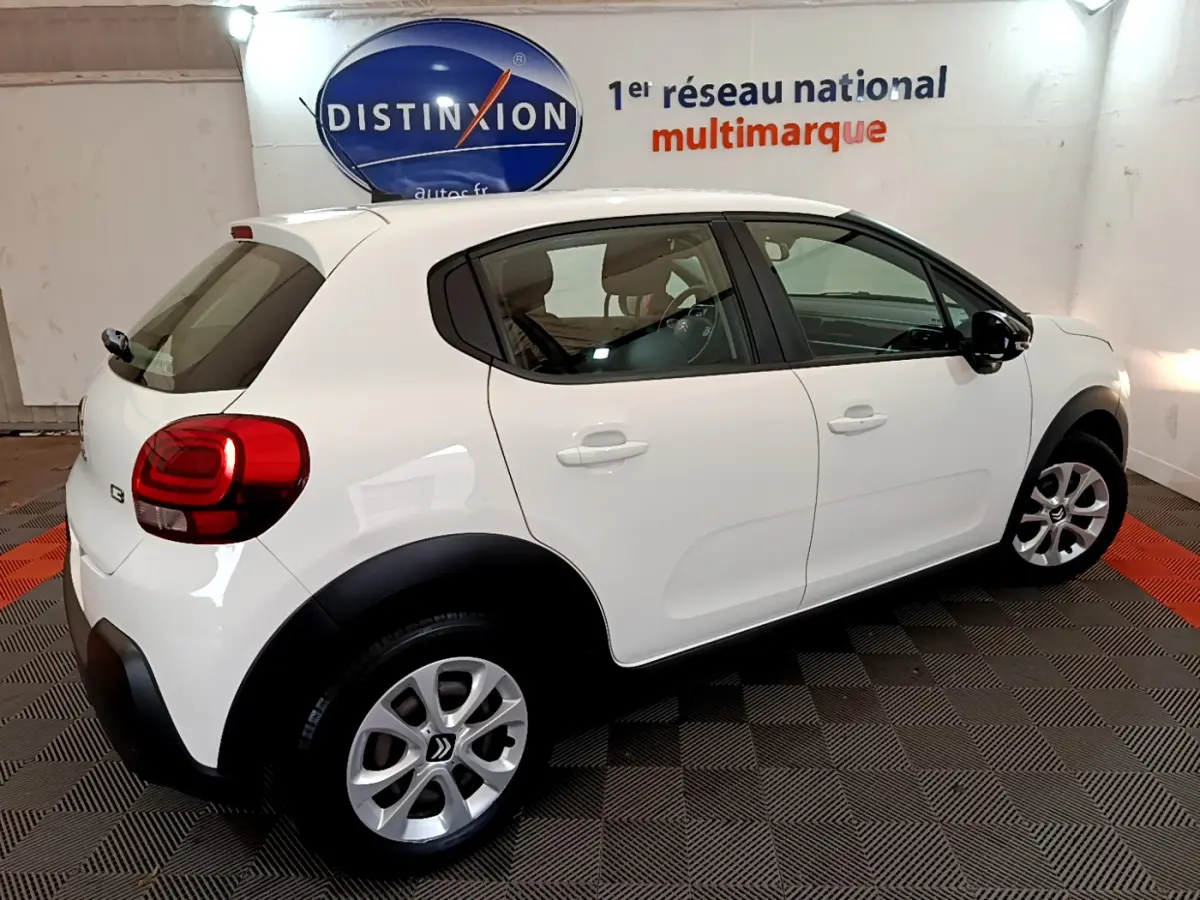 Citroën C3 blanche vue de côté droit arrière, avec jantes alliage et protections noires sur les passages de roues.