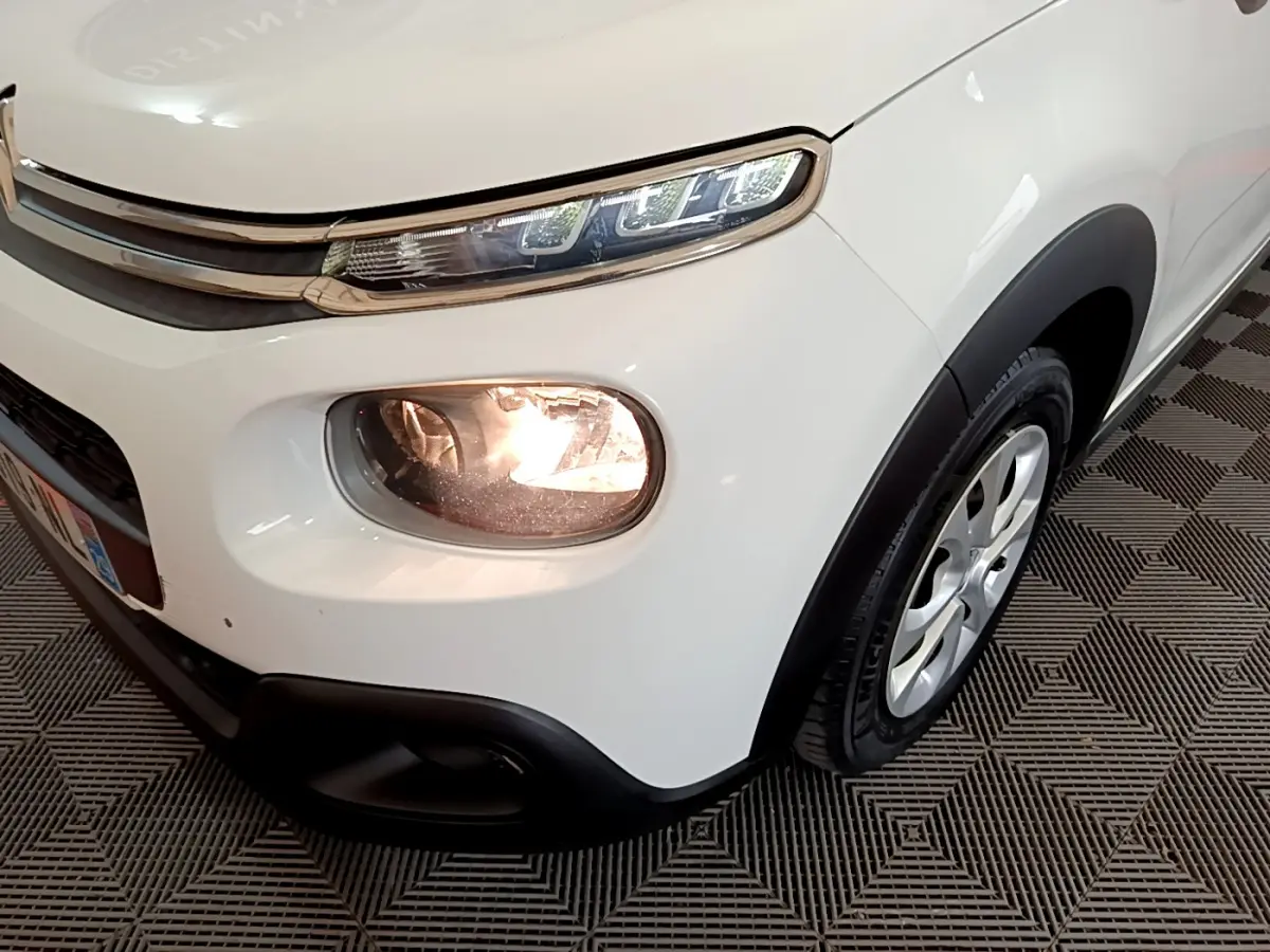 Gros plan sur l'avant droit blanc du Citroën C3 2019 avec phares allumés et jante alu visible.