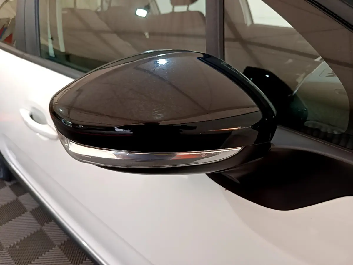 Rétroviseur noir côté gauche d'une Citroën C3 blanche, vue rapprochée sur la portière et la vitre.