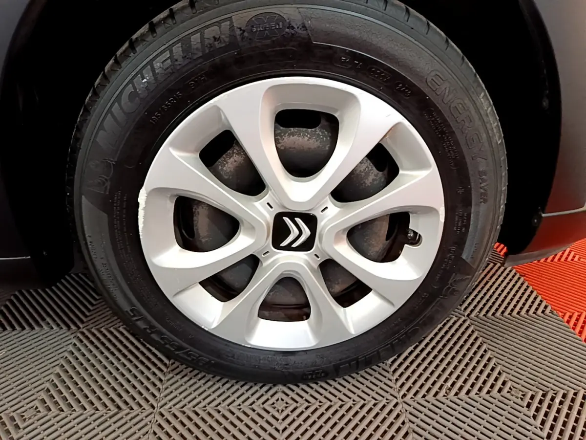 Gros plan sur la roue avant droite d'une Citroën C3 blanche, mettant en valeur la jante argentée au logo double chevron.