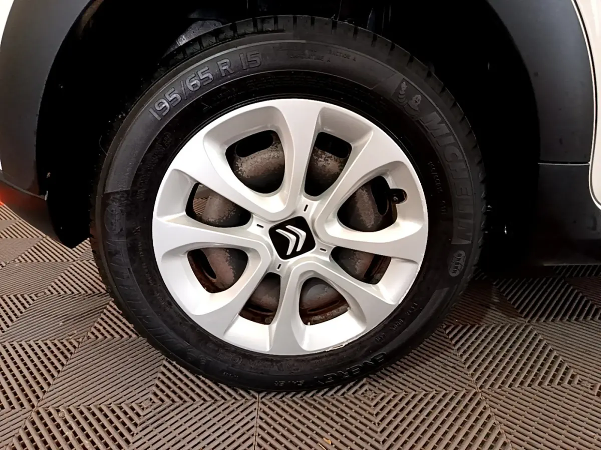 Gros plan sur la roue avant droite d'une Citroën C3 blanche avec jante alliage et logo Citroën central.