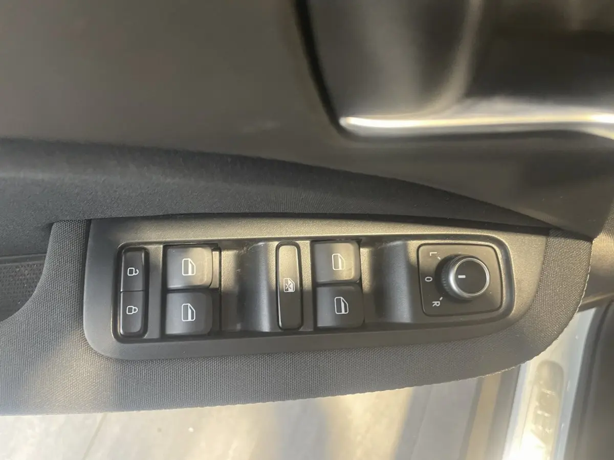 Vue rapprochée des commandes de vitres et rétroviseurs côté conducteur d'une LEAPMOTOR T03 Luxury blanche, 2025.