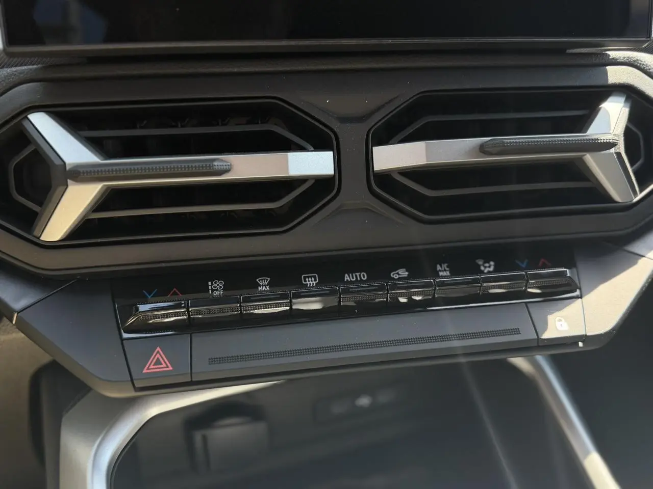 Gros plan sur la console centrale du Dacia Bigster 2026, montrant les aérateurs hexagonaux et les commandes de climatisation.