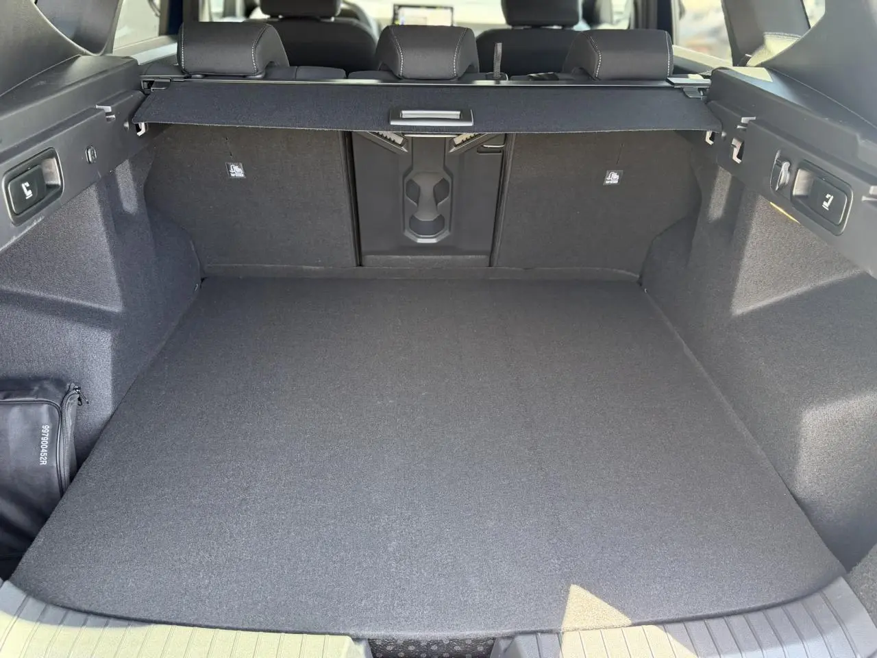 Coffre spacieux du Dacia Bigster Hybrid-G 150 4x4, vue arrière avec cache-bagages et banquette rabattable.