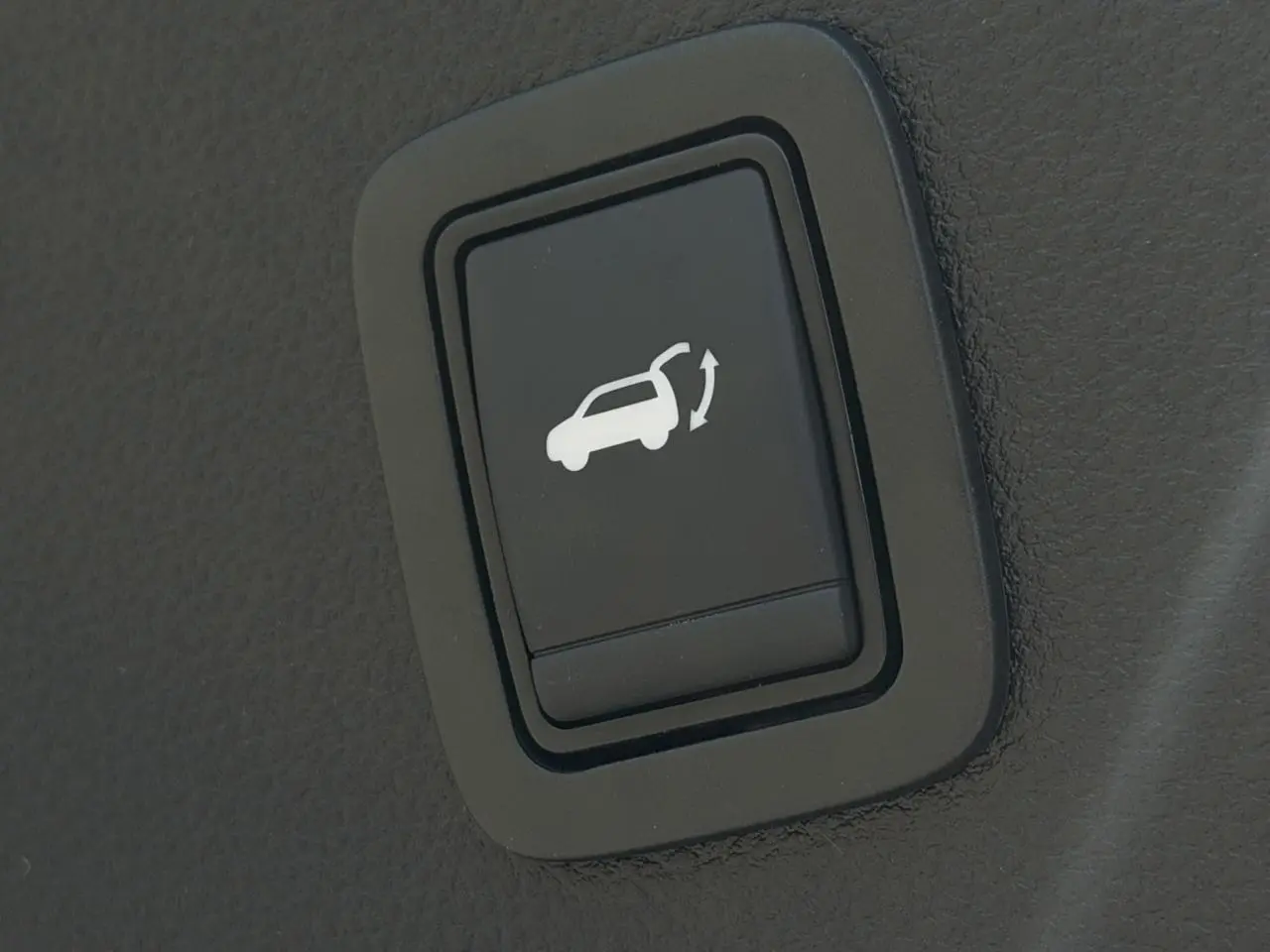 Bouton intérieur noir pour ouverture du hayon électrique sur Dacia Bigster Hybrid-G 150 bleu indigo.