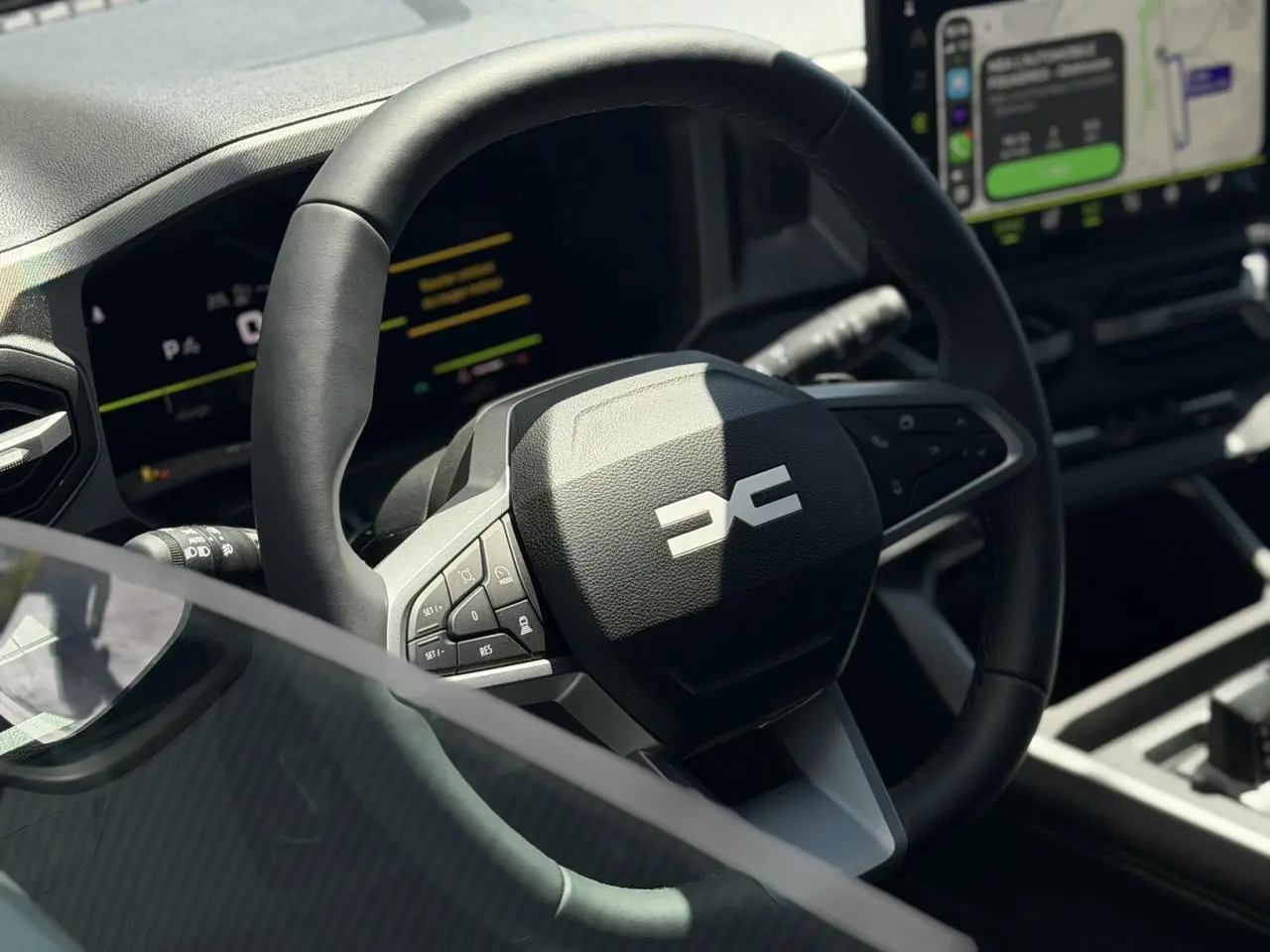 Gros plan sur le volant noir du Dacia Bigster 2026 avec tableau de bord numérique et écran tactile en arrière-plan.