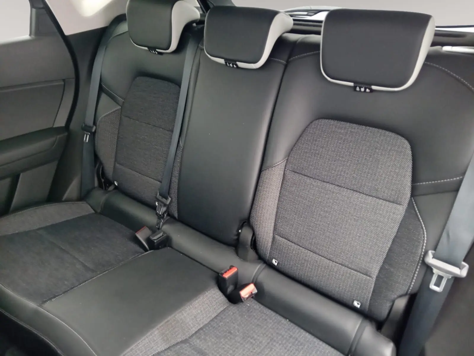 Vue rapprochée des sièges arrière en tissu gris et cuir noir du Renault Captur 2023, avec ceintures de sécurité visibles.