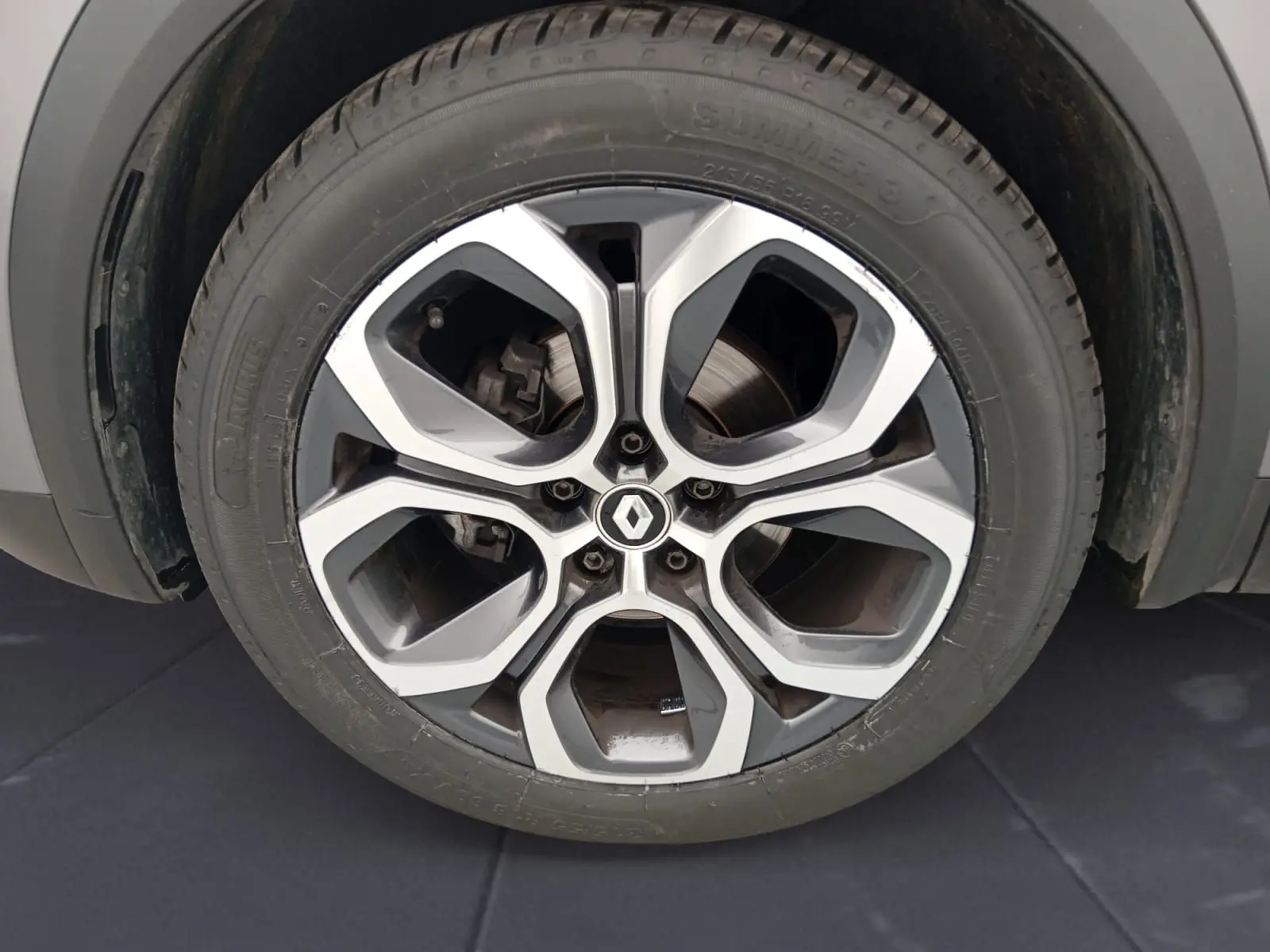 Gros plan sur la roue arrière gauche du Renault Captur gris Cassiopée/ noir, soulignant l'architecture de l'aile et le pneu.