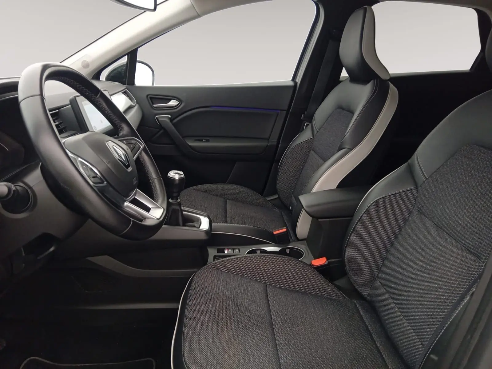 Vue intérieure côté conducteur du Renault Captur 1.3 Mild Hybrid 140 Techno avec sièges tissu gris et cuir noir, volant multifonction.