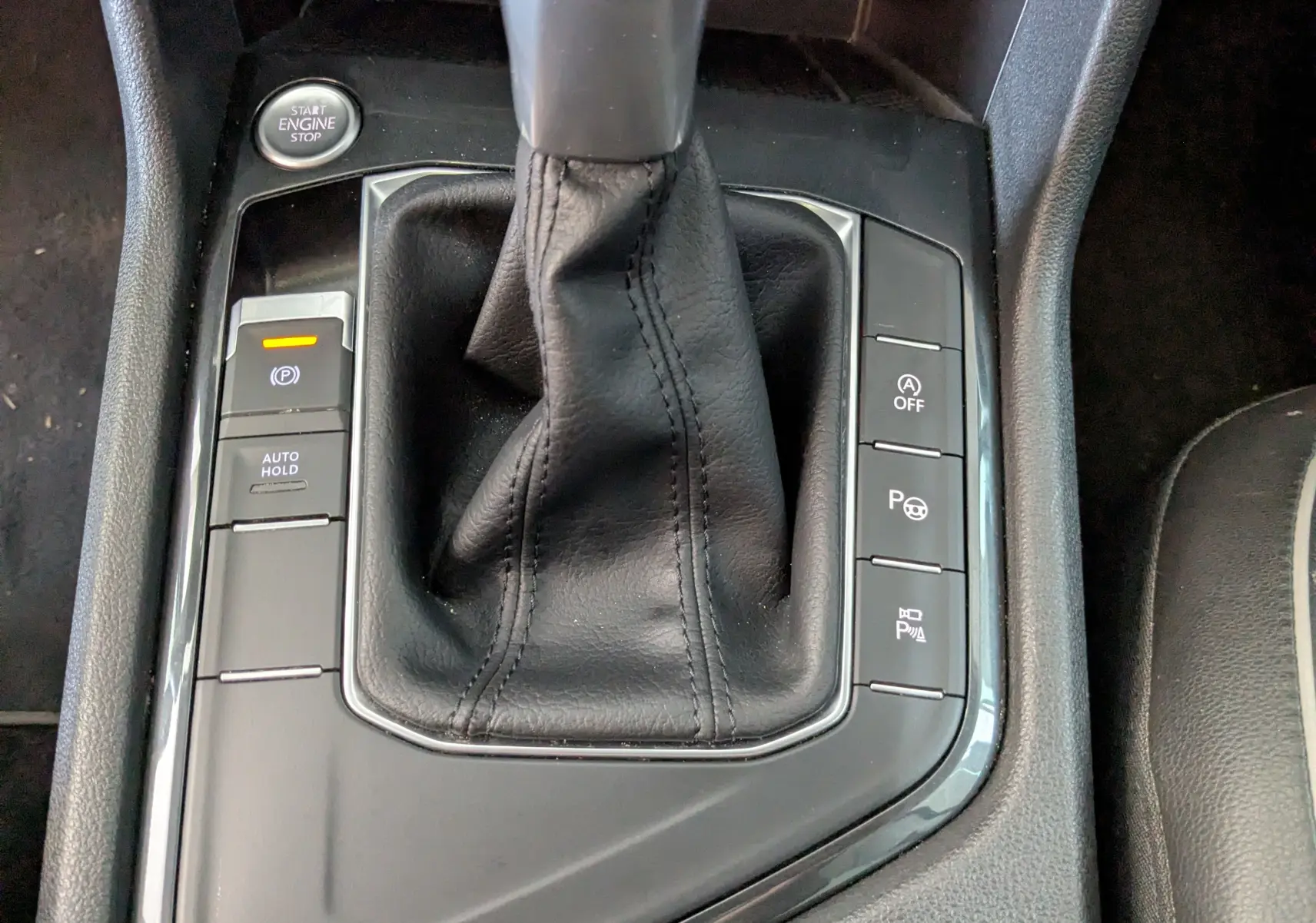 Gros plan sur la console centrale noire du Volkswagen Tiguan 2.0 TDI, avec levier de vitesse automatique et boutons de contrôle.