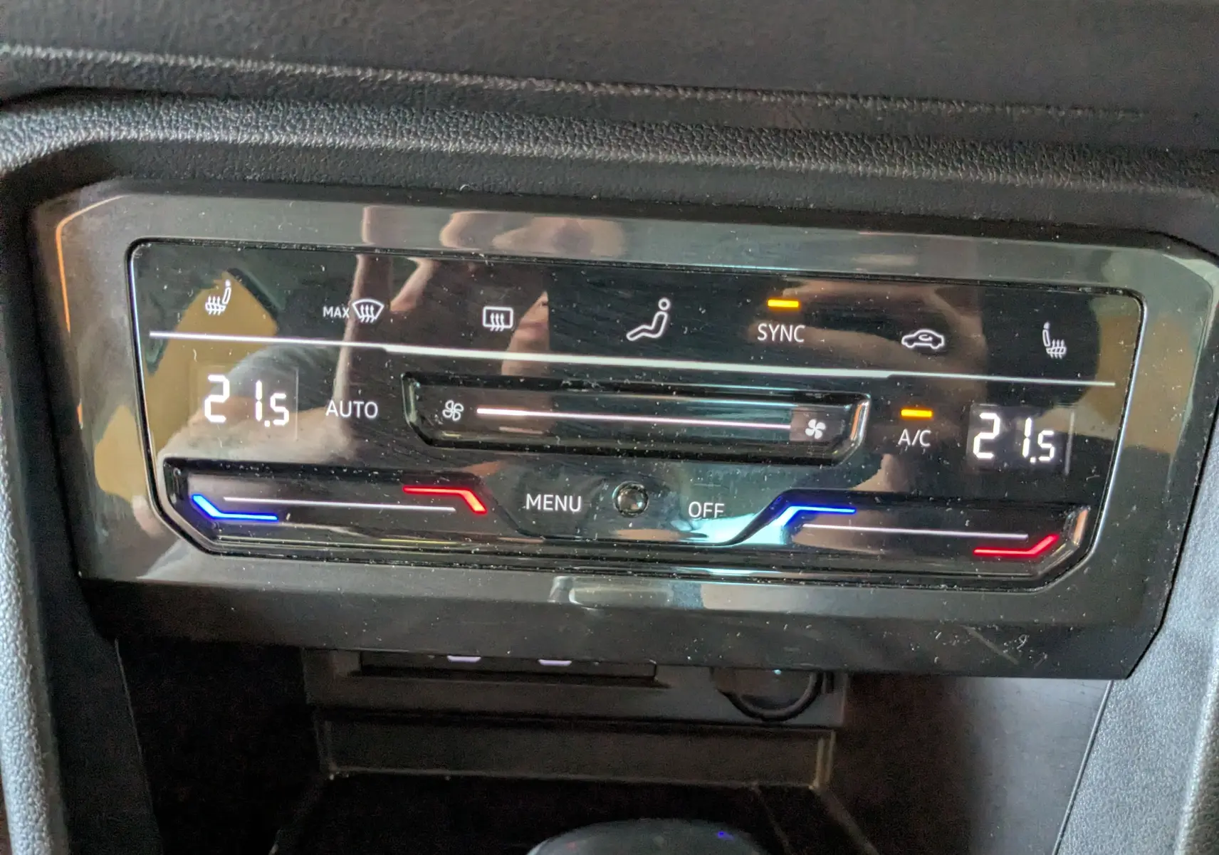 Gros plan sur la commande de climatisation digitale du Volkswagen Tiguan noir, affichant 21,5°C et options chauffantes activées.
