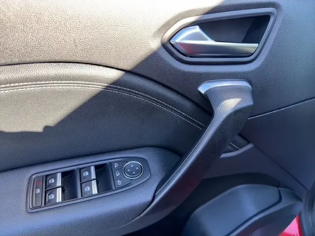 Vue rapprochée de la porte avant gauche du Renault Captur rouge 2024, montrant la poignée et les commandes des vitres électriques.