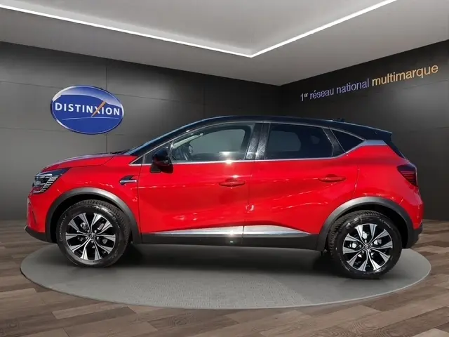 Renault Captur Techno TCe 90 rouge vue de profil côté gauche en intérieur, avec jantes noires et toit noir contrasté.