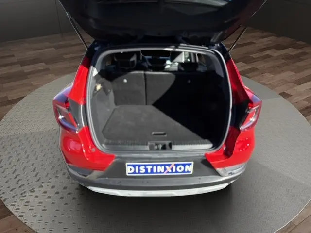 Vue arrière ouverte du coffre d'un Renault Captur rouge 2024, montrant l'espace de chargement vide et la plaque Distinxion.