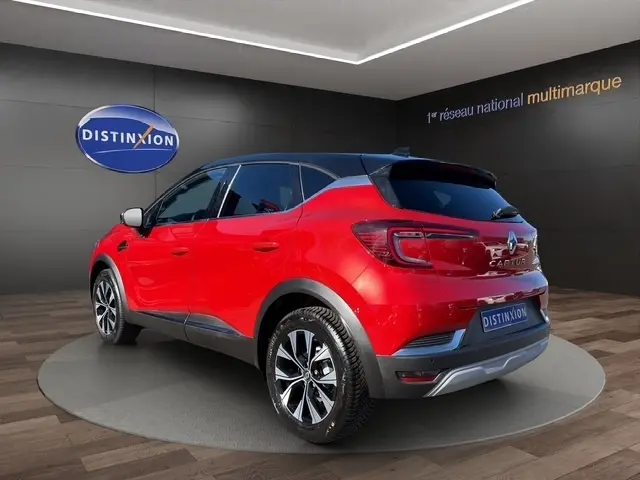 Vue 3/4 arrière droite d’un Renault Captur Techno TCe 90 rouge avec toit noir et jantes alliage bicolores.