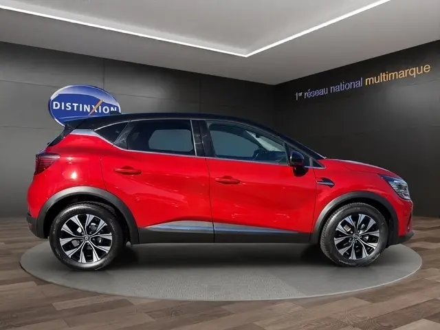 Profil latéral droit du Renault Captur Techno TCe 90 rouge 2024 avec toit noir et jantes alliage bicolores.