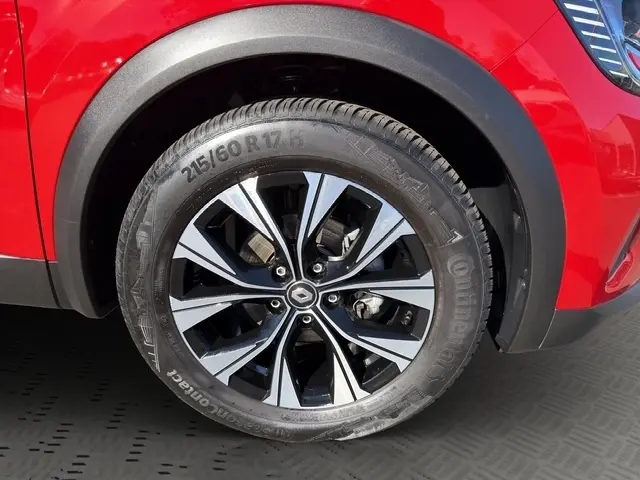 Gros plan sur la roue avant droite d’un Renault Captur rouge 2024 avec jante alliage bicolore et logo Renault central.