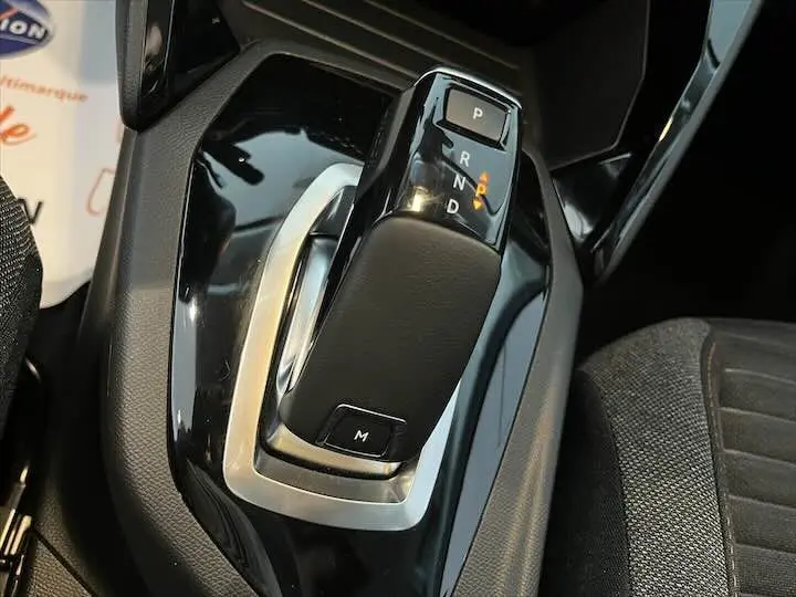 Le levier de vitesses automatique noir brillant de la Peugeot 208 1.2 100 CH vue en gros plan intérieur.