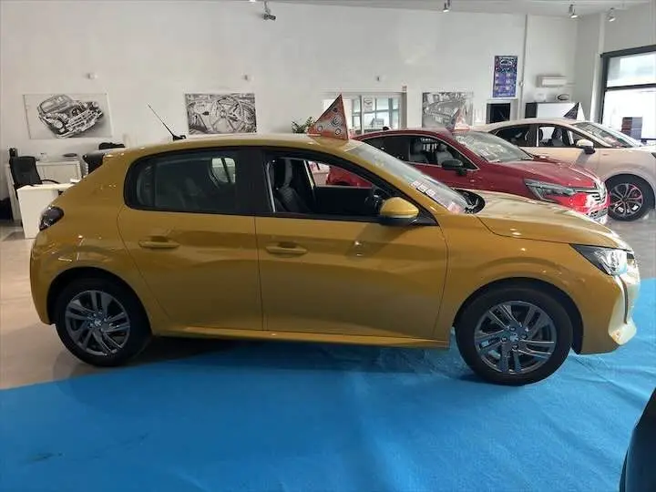 Peugeot 208 jaune Faro Metal vue de profil côté gauche dans un showroom avec d'autres voitures en arrière-plan.