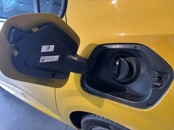 Gros plan sur la trappe à carburant ouverte côté gauche d'une Peugeot 208 jaune Faro Metal essence 2021.