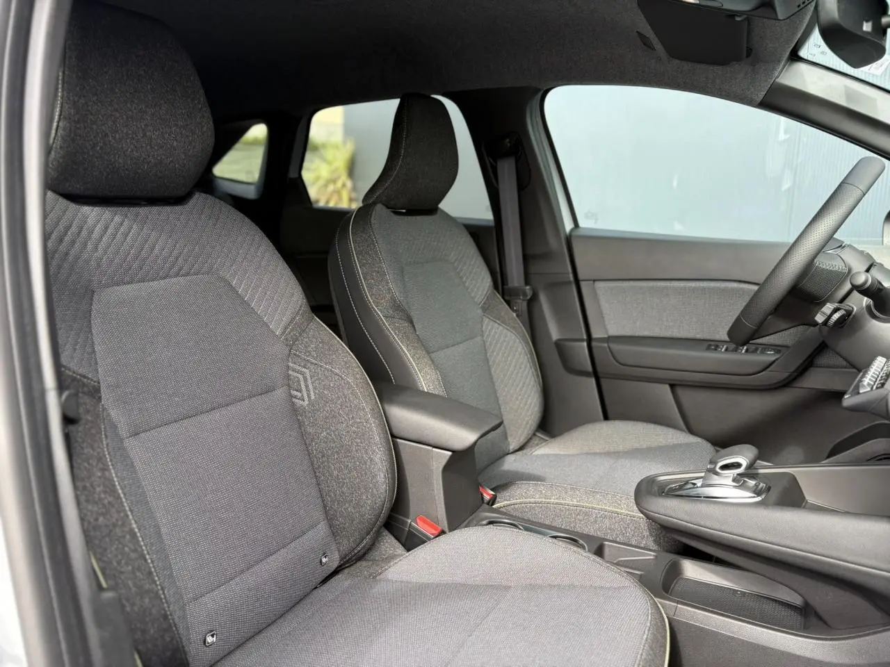 Vue intérieure côté gauche sur les sièges avant gris foncé et la console centrale du Renault Symbioz E-Tech 2025