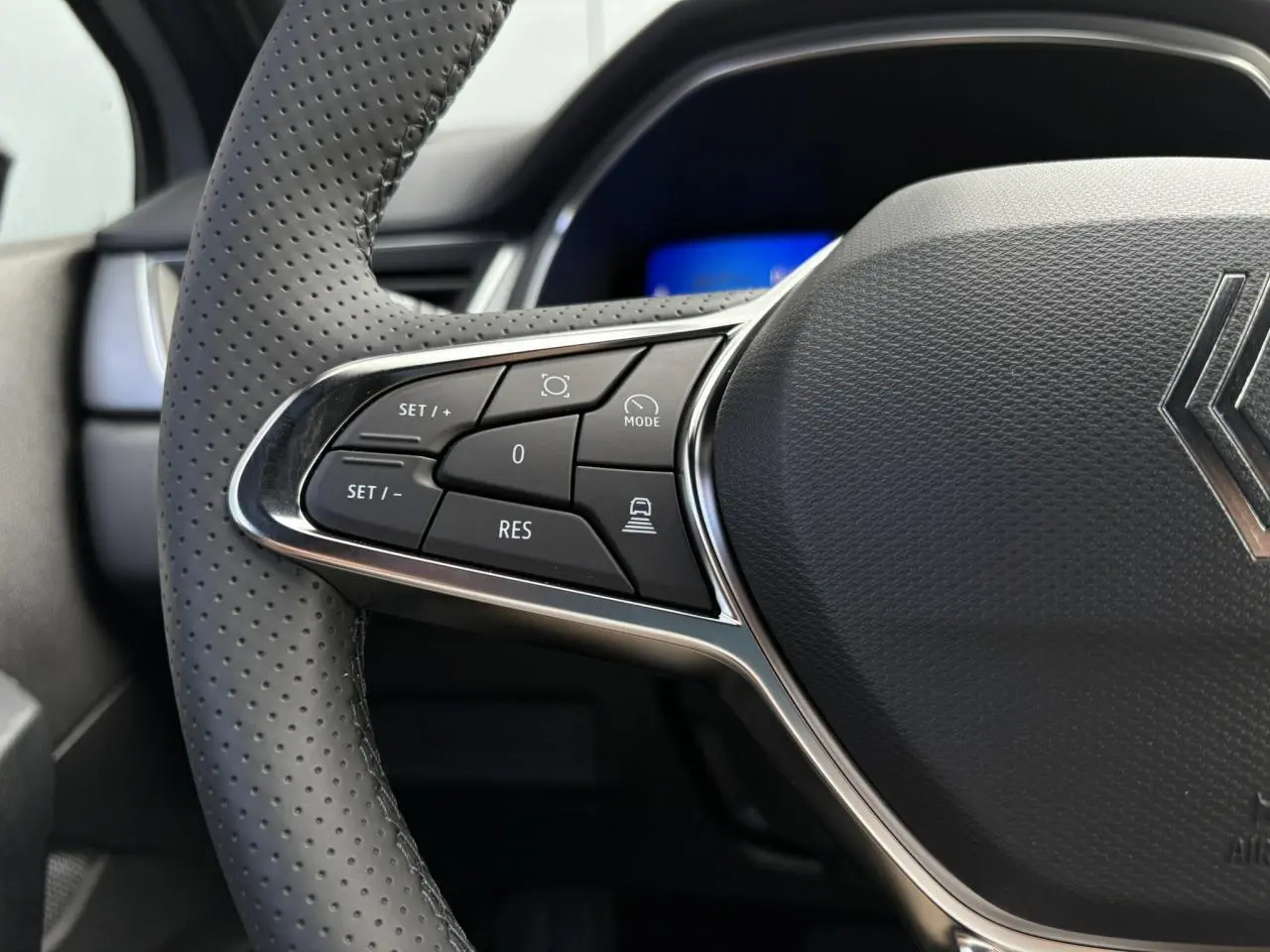 Gros plan sur le volant en cuir perforé gris du Renault Symbioz 2025, avec commandes multifonctions côté gauche.