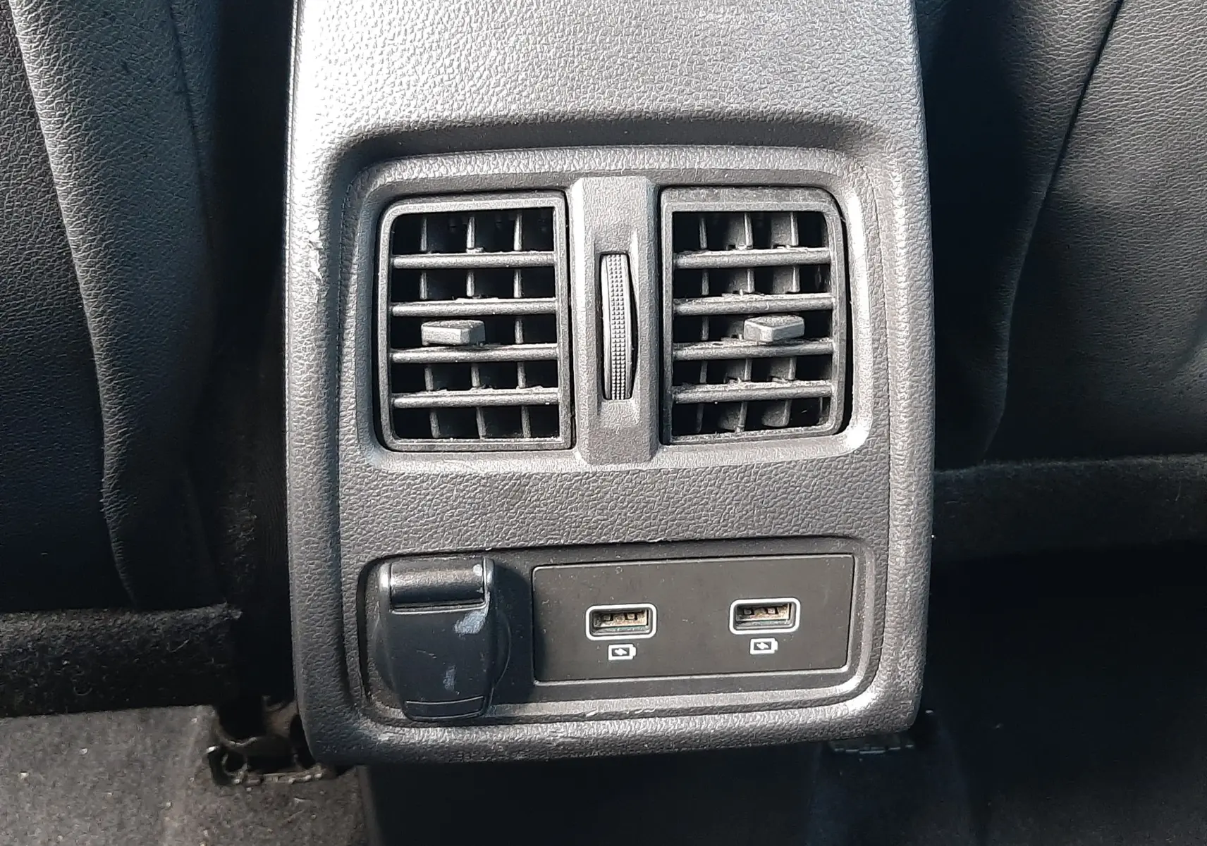 Gros plan sur la console arrière noire du Renault Captur 2020, avec deux bouches d'aération et deux ports USB visibles.