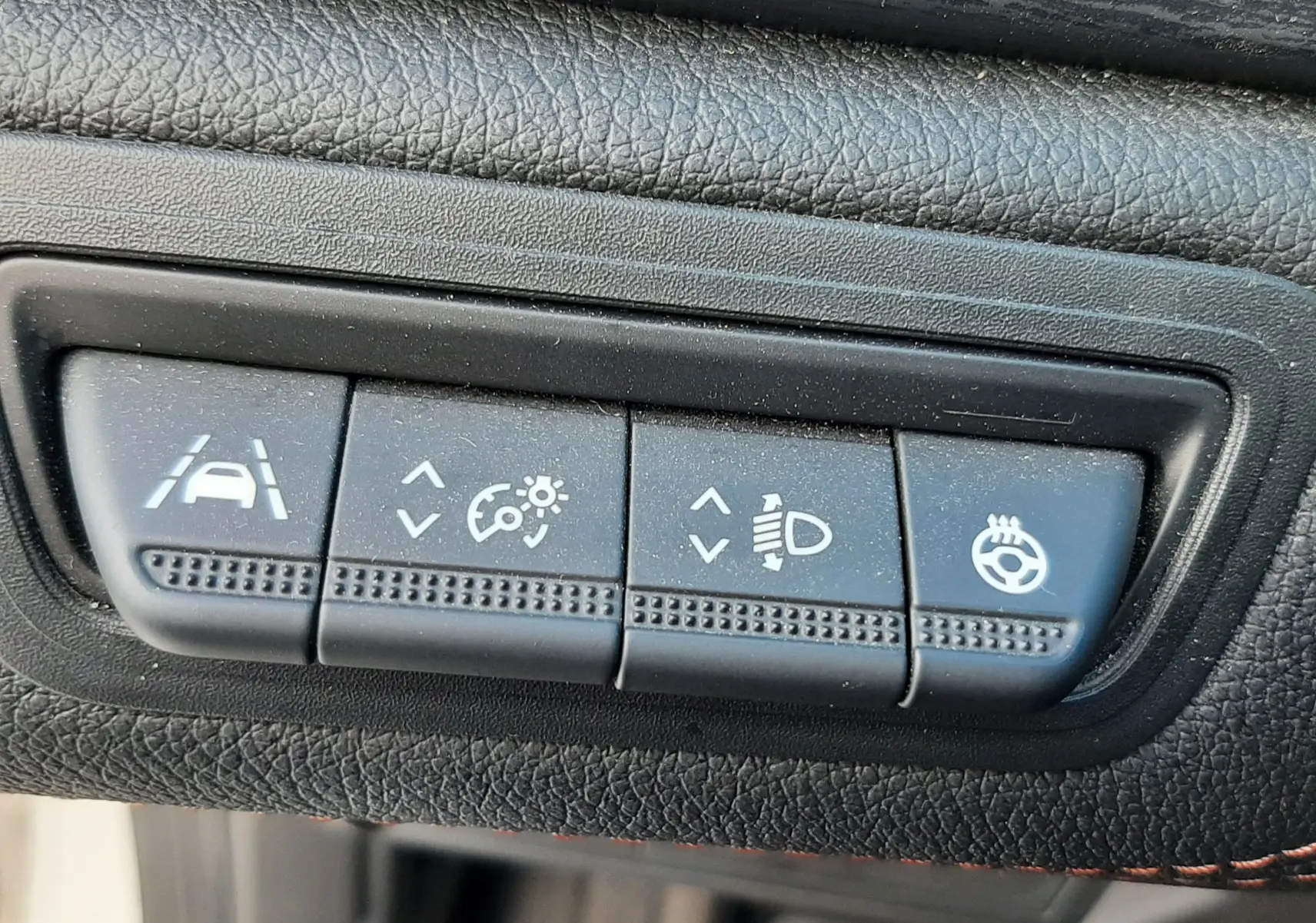 Gros plan sur les boutons de réglages d'assistance et éclairage du tableau de bord du Renault Captur blanc toit noir.