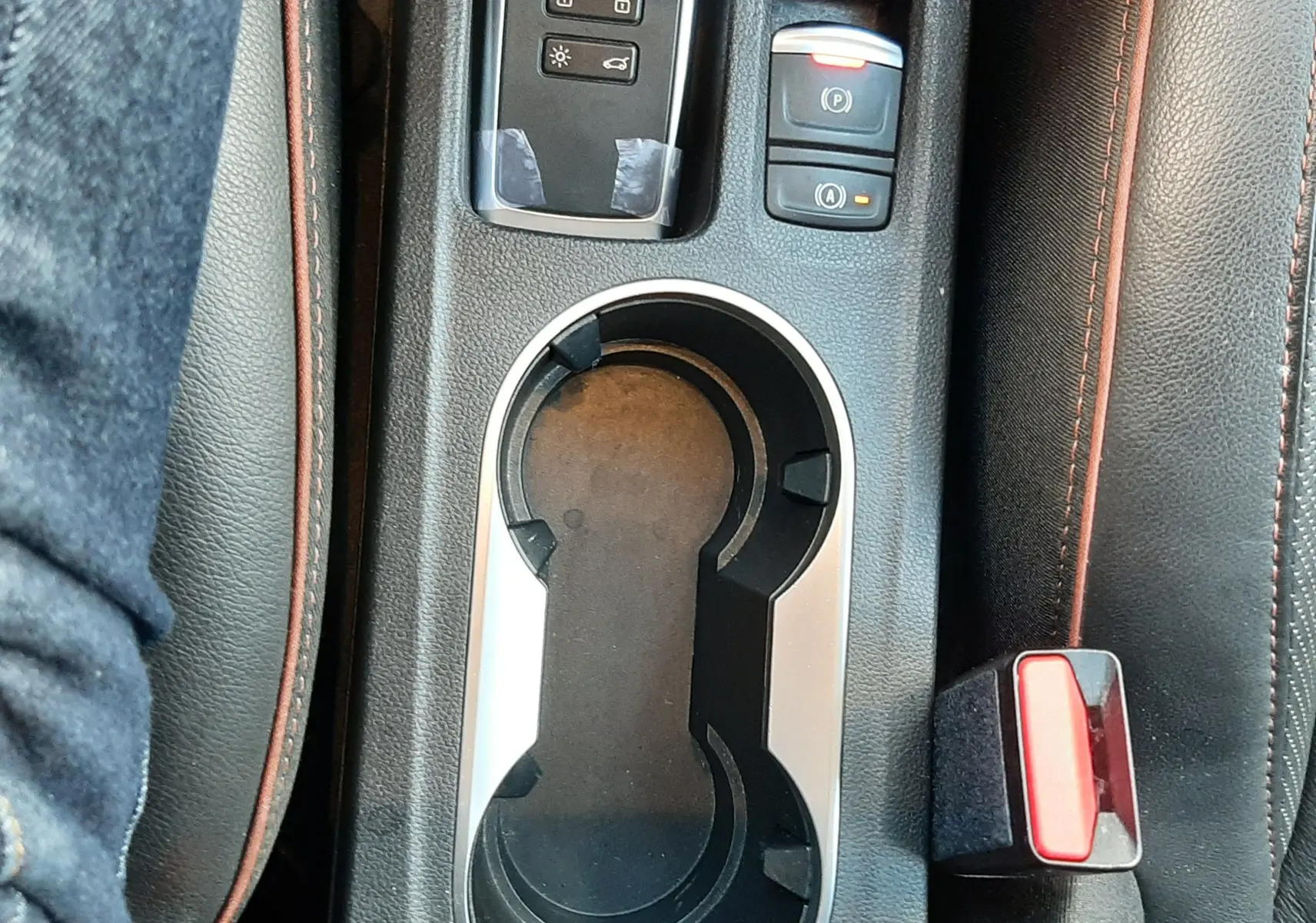 Gros plan sur la console centrale noire du Renault Captur 2020, avec porte-gobelets, bouton frein à main et clé à télécommande.