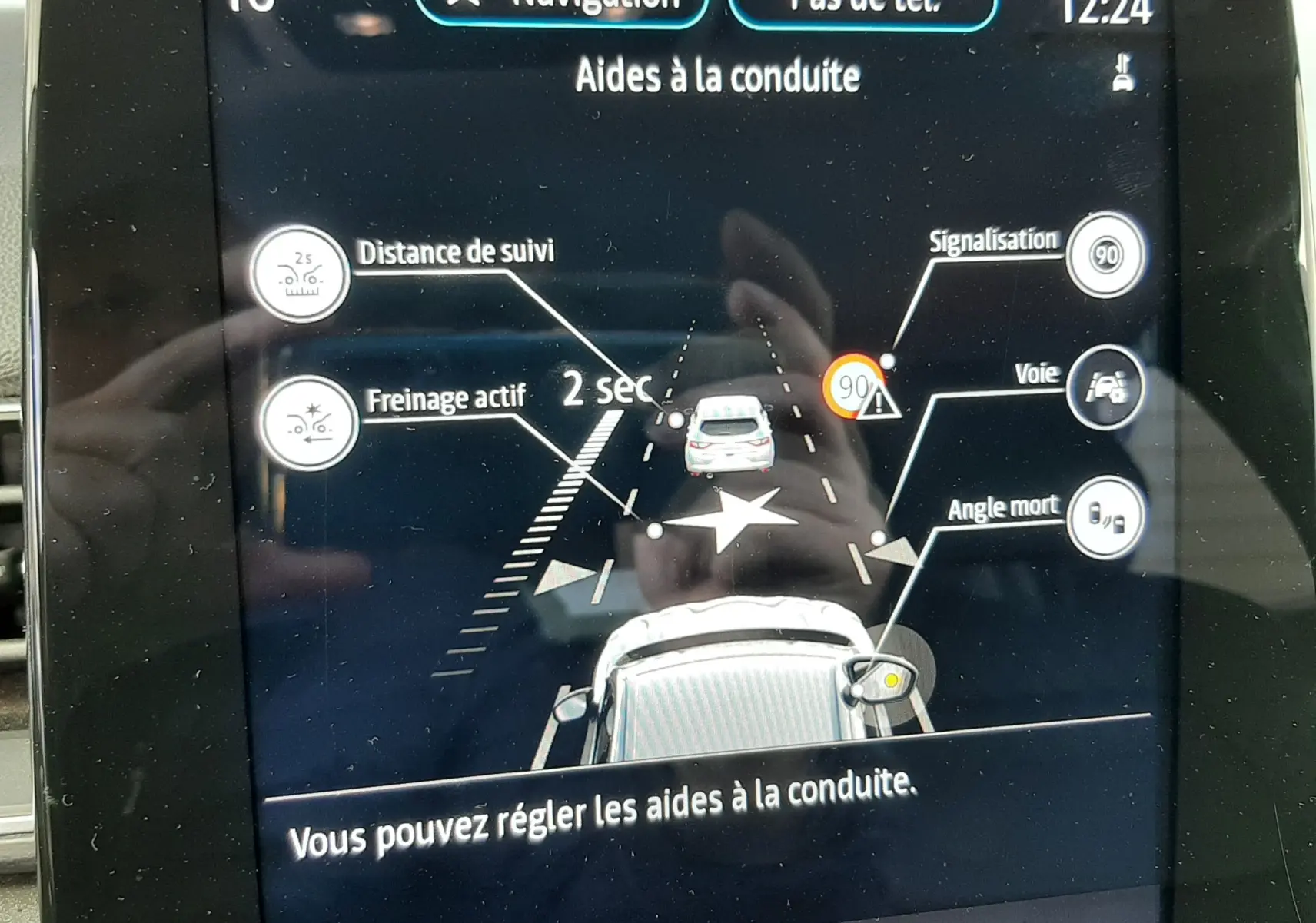 Écran tactile intérieur du Renault Captur blanc/toit noir affichant les aides à la conduite avec navigation et alertes visibles.