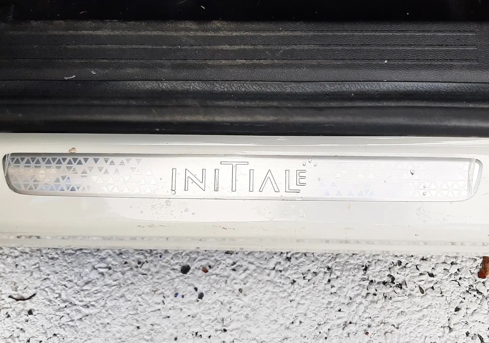 Gros plan sur la plaque de seuil de porte blanche avec inscription "INITIALE" du Renault Captur 2020 finition Initial Paris.