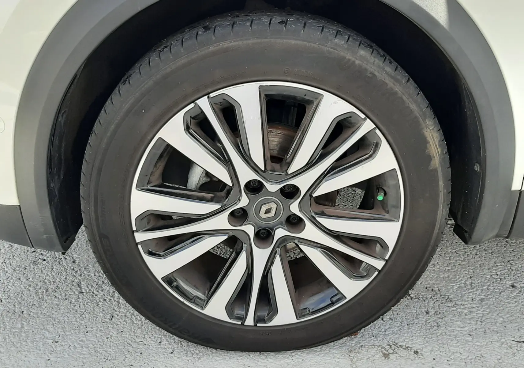 Gros plan sur la roue avant droite du Renault Captur blanc avec jante alliage au design moderne.