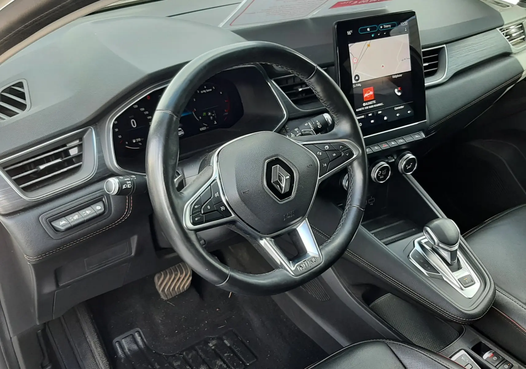 Vue intérieure côté conducteur du Renault Captur 2020, tableau de bord noir avec écran tactile vertical et volant cuir.