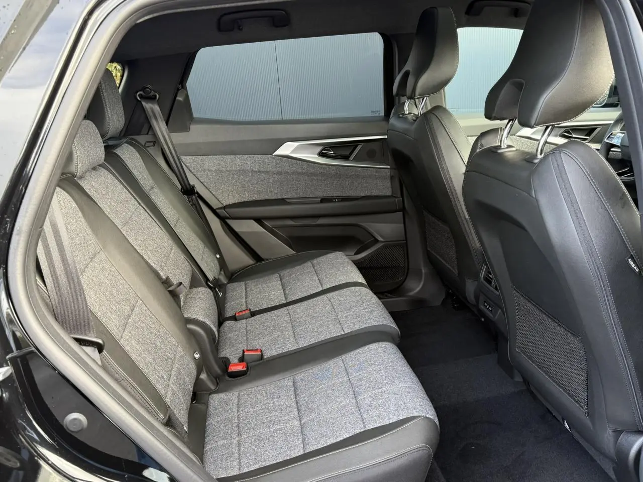 Vue intérieure côté gauche des sièges arrière gris clair et tissu du Renault Espace VI noir étoilé avec habillage de porte moderne.