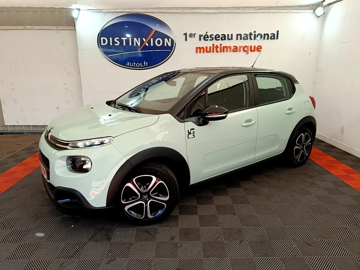 Citroën C3 PureTech 82 vert vue 3/4 avant droit, avec jantes noires et toit noir contrasté dans un showroom.