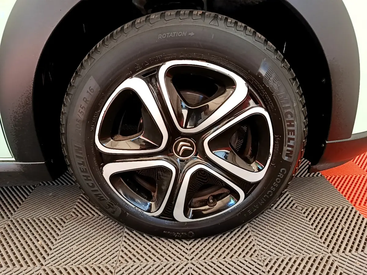Gros plan sur la roue avant droite d'une Citroën C3 verte, jante noire et argent avec pneu Michelin.