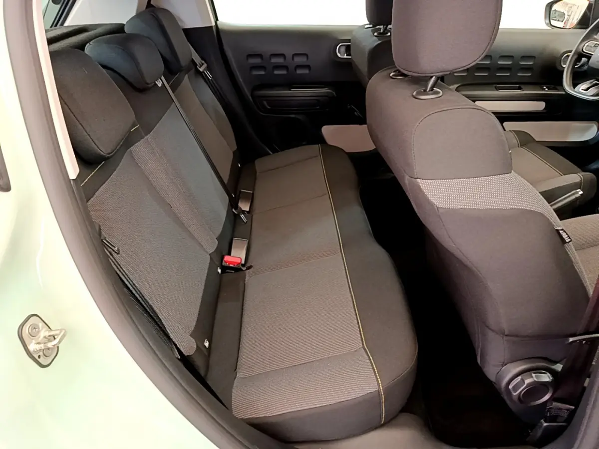 Vue intérieure côté gauche montrant la banquette arrière et les sièges avant noirs de la Citroën C3 vert 2019.