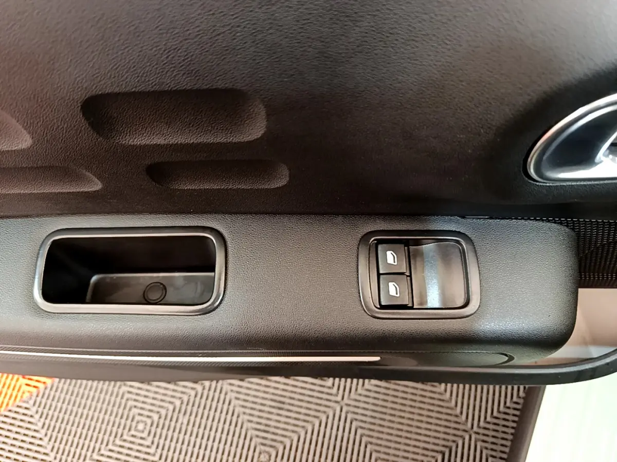 Gros plan sur la commande des vitres électriques côté gauche de la porte intérieure d'une Citroën C3 vert 2019.