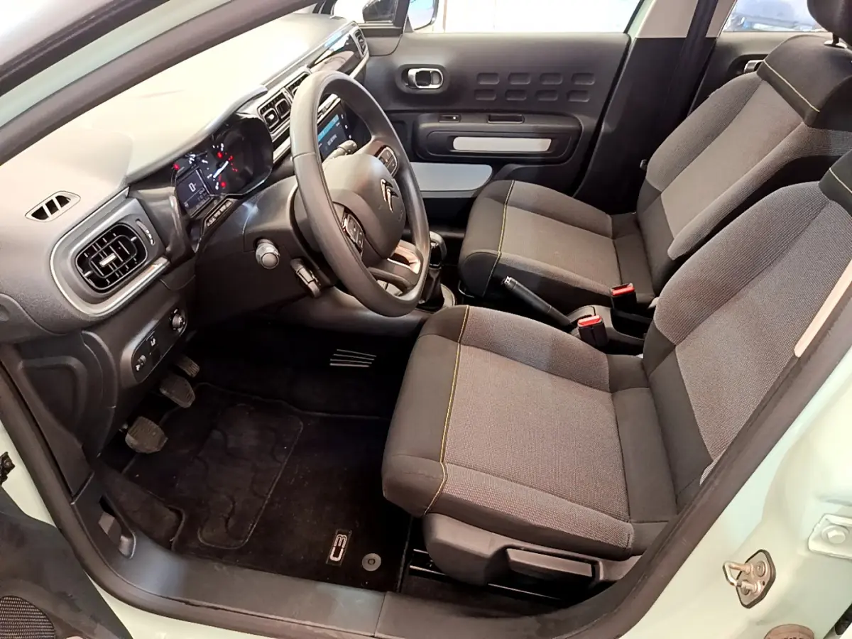 Intérieur avant de la Citroën C3 vert clair, sièges gris avec surpiqûres jaunes et tableau de bord moderne tactile.