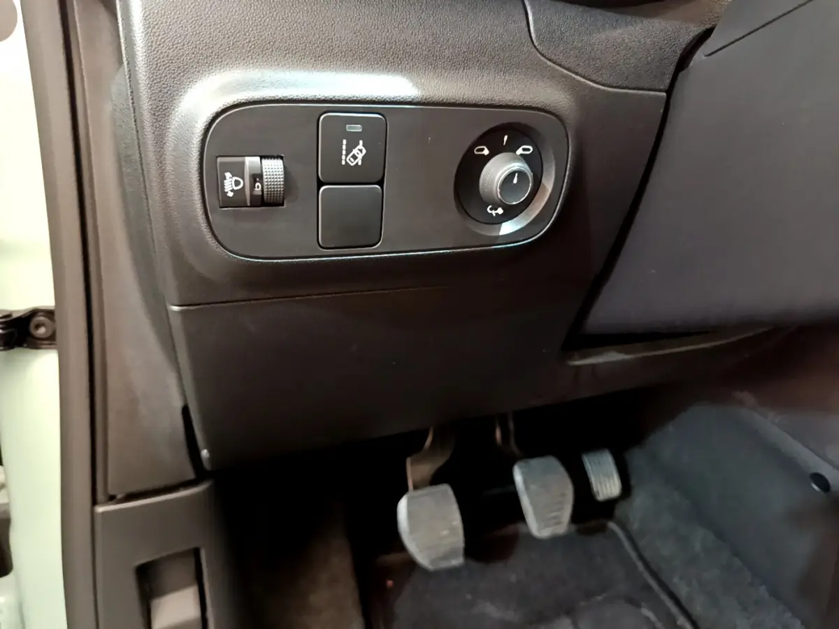 Détail des commandes d'éclairage et réglage des rétroviseurs côté gauche dans l'habitacle noir d'une Citroën C3 verte.