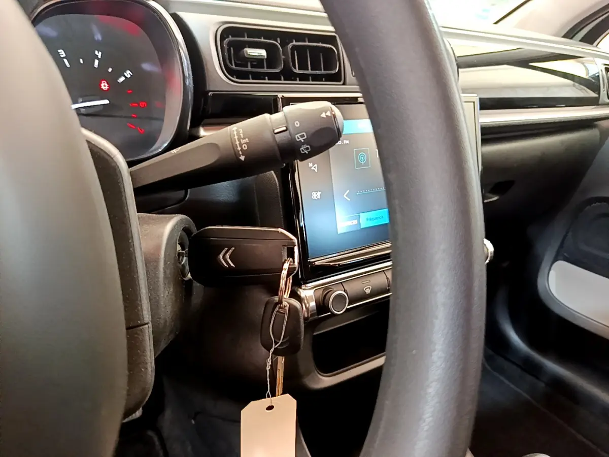 Vue intérieure centrée sur le volant et l'écran tactile de la Citroën C3 PureTech 82, avec clé insérée au contacteur.