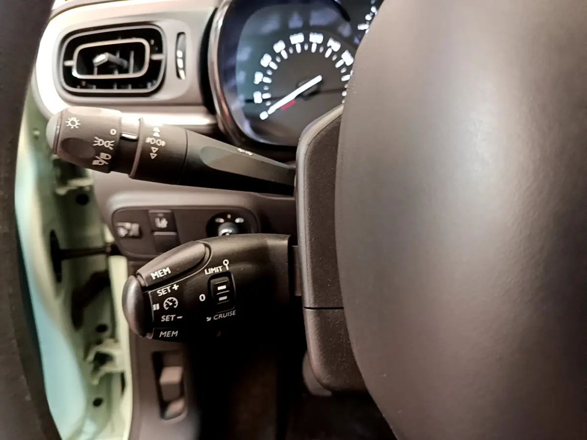 Gros plan sur le volant et commandes au volant côté gauche d'une Citroën C3 vert 2019, avec tableau de bord visible.