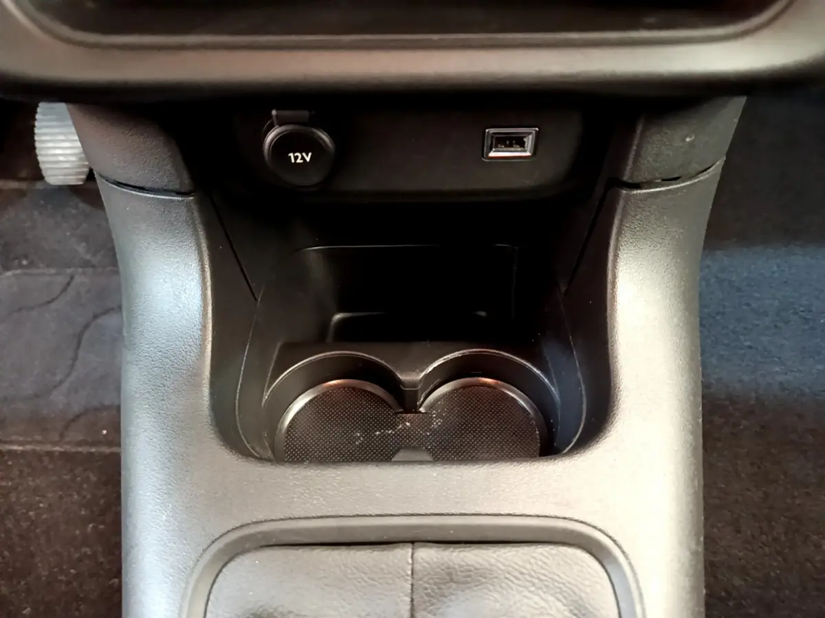 Gros plan sur la console centrale noire avec prise 12V, port USB et porte-gobelets de la Citroën C3 2019.