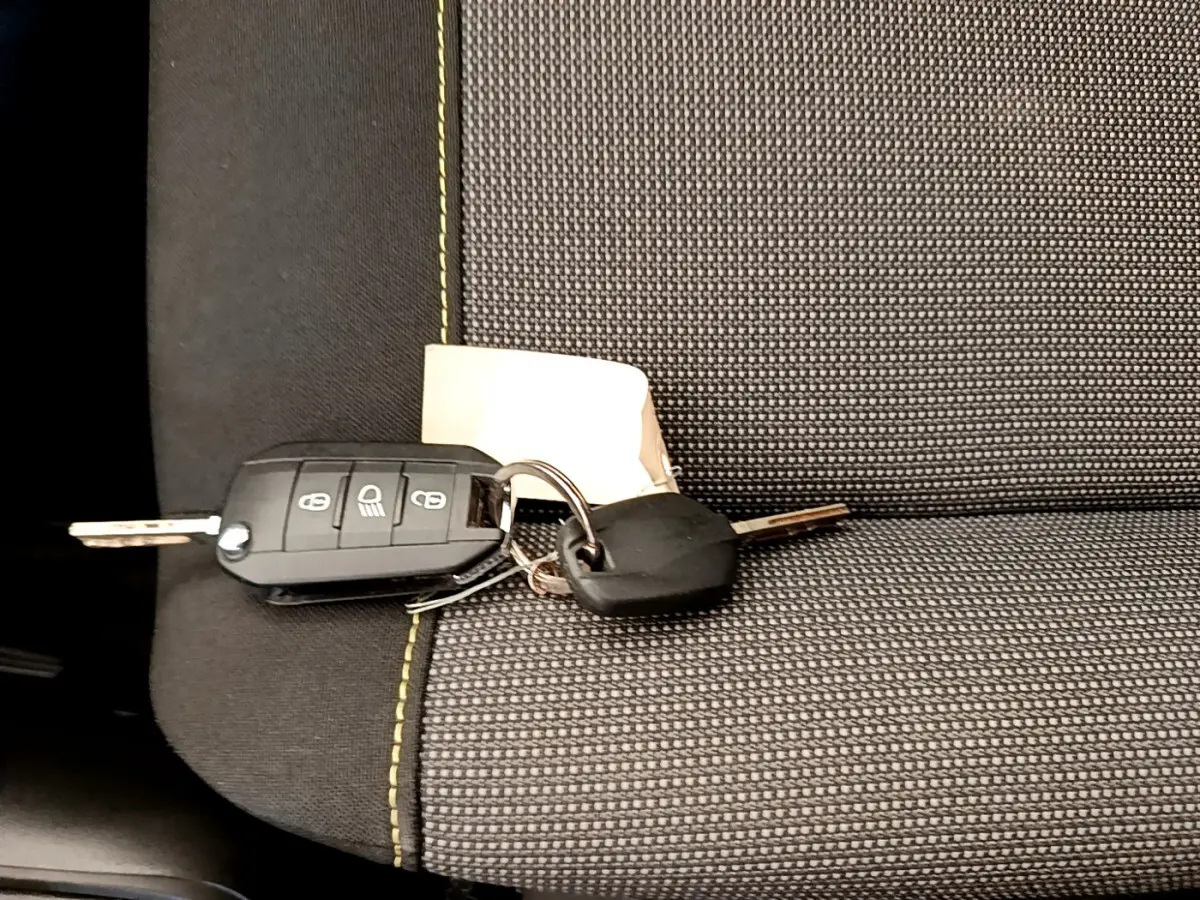 Clé de voiture Citroën C3 posée sur siège tissu gris à surpiqûres vertes, vue rapprochée de l'intérieur